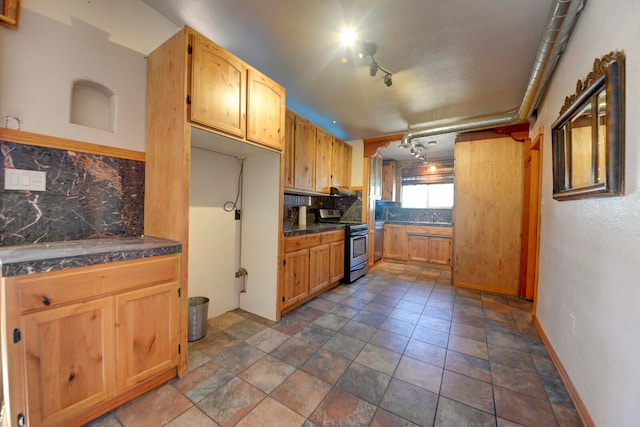 kitchen featuring stainless steel gas range, sink, decorative backsplash, and track lighting