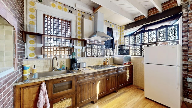 kitchen featuring white refrigerator, beamed ceiling, sink, ventilation hood, and stainless steel gas stovetop