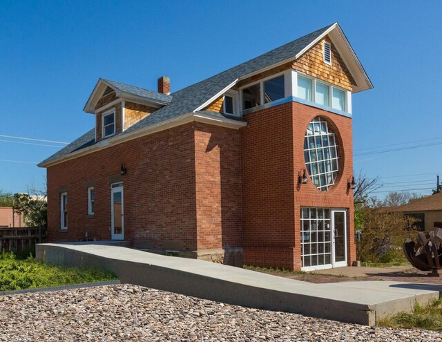 view of property exterior with driveway, a chimney, and brick siding