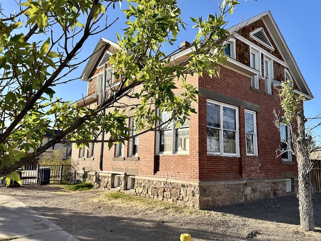 view of side of home with brick siding and fence