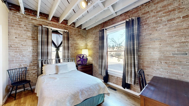 bedroom with beam ceiling, visible vents, brick wall, wood finished floors, and baseboards