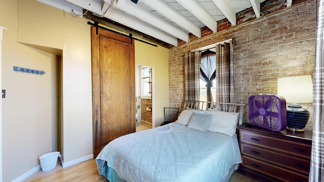 bedroom featuring brick wall, a barn door, baseboards, and beam ceiling