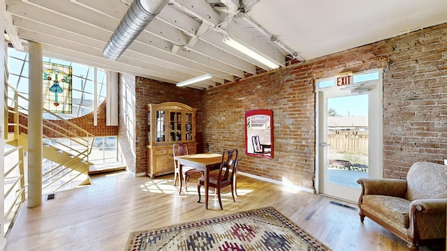 dining space featuring brick wall, light wood finished floors, visible vents, and track lighting