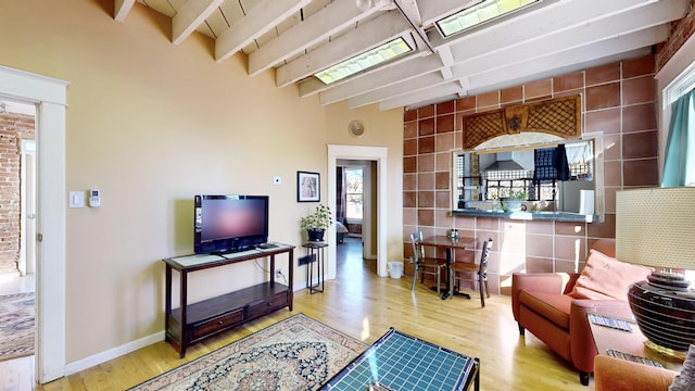 living room with beam ceiling, baseboards, and wood finished floors