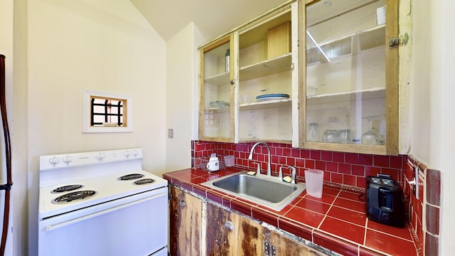 kitchen with tasteful backsplash, tile counters, a sink, and white range with electric cooktop