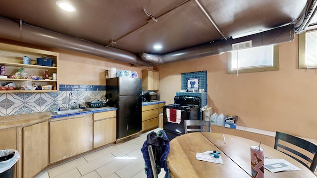 kitchen with light tile patterned floors, visible vents, black appliances, light brown cabinets, and a sink