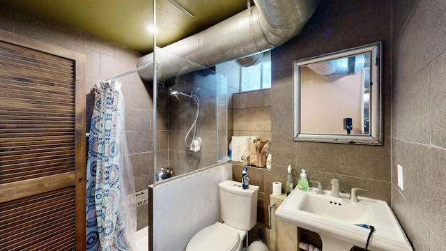 full bath with toilet, a sink, tile walls, a tile shower, and decorative backsplash