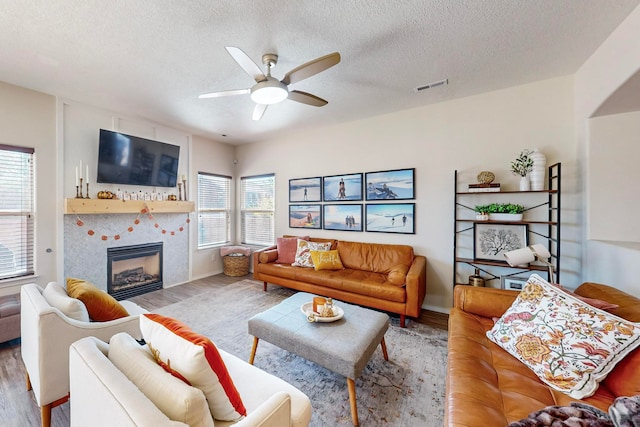 living room featuring a wealth of natural light, a tiled fireplace, hardwood / wood-style flooring, and ceiling fan