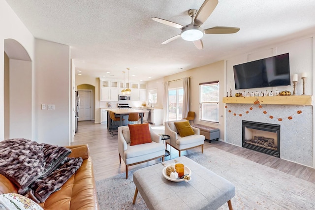 living room featuring ceiling fan, a textured ceiling, and light hardwood / wood-style flooring