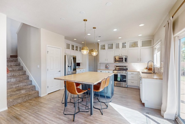 kitchen featuring stainless steel appliances, sink, a kitchen island, and white cabinets