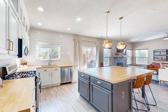 kitchen featuring gray cabinetry, stainless steel appliances, sink, a center island, and white cabinetry