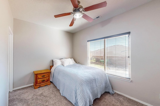 carpeted bedroom featuring multiple windows, a textured ceiling, and ceiling fan