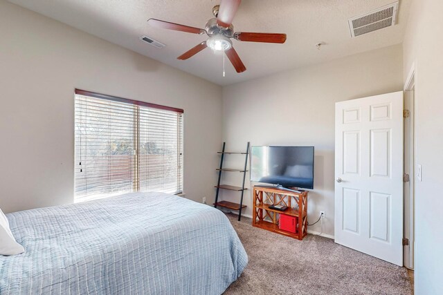 bedroom featuring ceiling fan, a textured ceiling, and light colored carpet