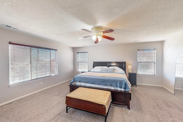 bedroom featuring light carpet, a textured ceiling, and ceiling fan