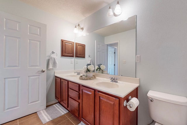 bathroom featuring vanity, a textured ceiling, toilet, and tile patterned flooring