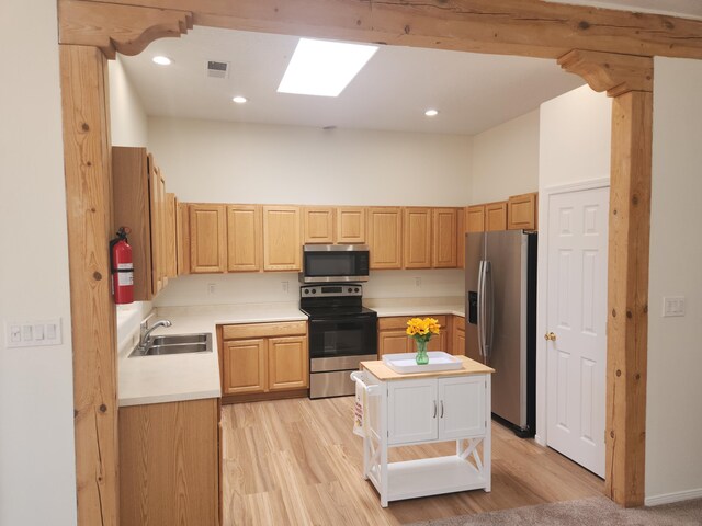 kitchen featuring light brown cabinetry, sink, a center island, light hardwood / wood-style floors, and stainless steel appliances