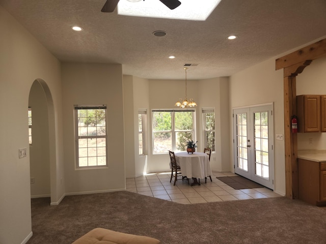 dining space featuring ceiling fan with notable chandelier, light colored carpet, a textured ceiling, and french doors