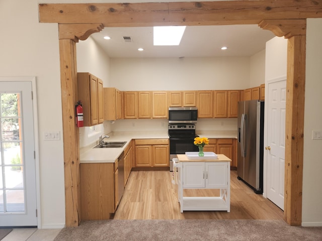 kitchen featuring sink, a towering ceiling, a skylight, stainless steel appliances, and light brown cabinets