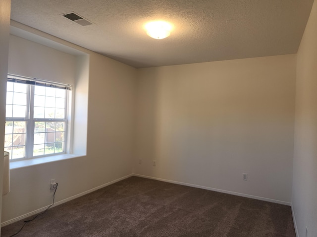 empty room featuring dark carpet and a textured ceiling