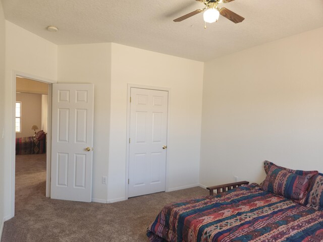 carpeted bedroom featuring ceiling fan and a textured ceiling