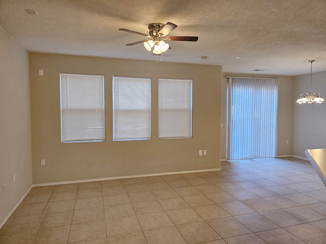 tiled empty room with a textured ceiling and ceiling fan with notable chandelier