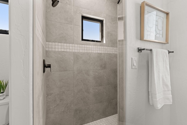 bathroom featuring tiled shower and toilet