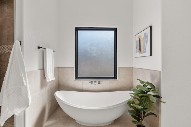 bathroom featuring tile patterned floors, a washtub, and tile walls