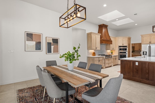 dining room featuring an inviting chandelier, light tile patterned floors, sink, and a skylight