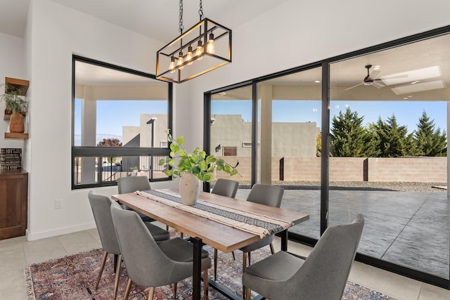 dining space with light tile patterned flooring, a healthy amount of sunlight, and ceiling fan with notable chandelier