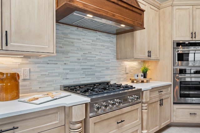 kitchen featuring custom exhaust hood, light brown cabinets, decorative backsplash, and stainless steel appliances