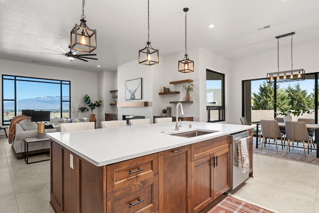 kitchen with hanging light fixtures, sink, an island with sink, and stainless steel dishwasher