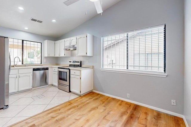 kitchen featuring light hardwood / wood-style floors, lofted ceiling, white cabinets, sink, and appliances with stainless steel finishes