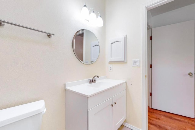 bathroom with wood-type flooring, toilet, and vanity