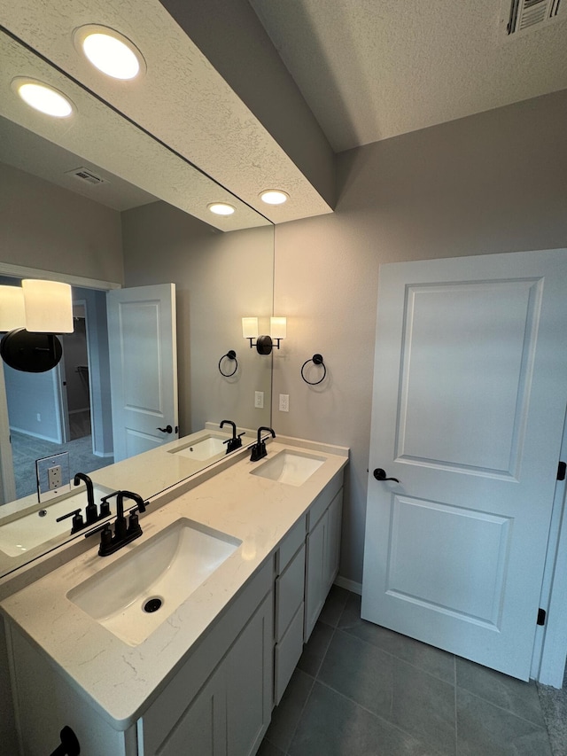 bathroom with tile patterned floors, vanity, and a textured ceiling