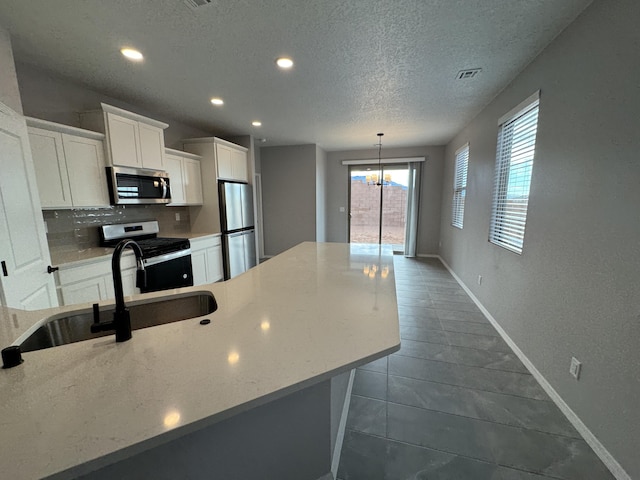 kitchen featuring light stone countertops, appliances with stainless steel finishes, a textured ceiling, sink, and white cabinetry