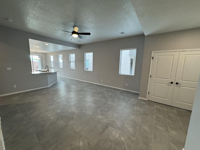 empty room featuring a textured ceiling, ceiling fan, and sink