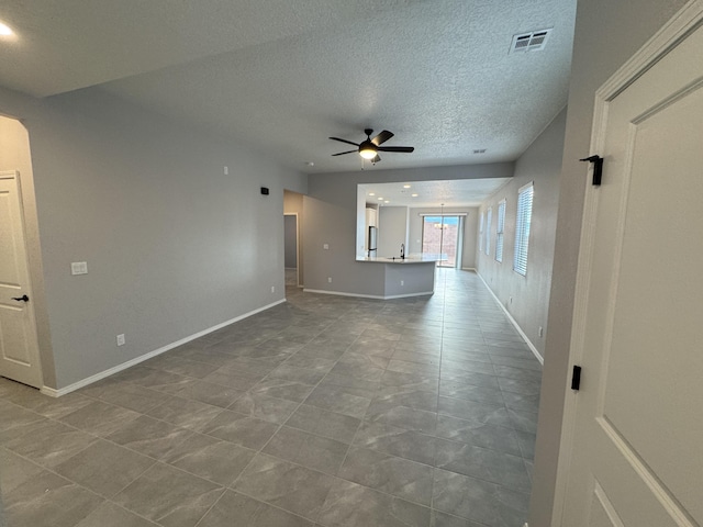 unfurnished living room with a textured ceiling, ceiling fan, and sink