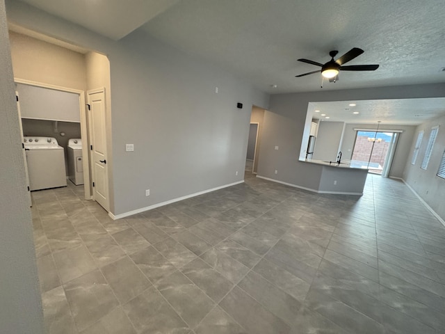 unfurnished living room featuring a textured ceiling, separate washer and dryer, and ceiling fan