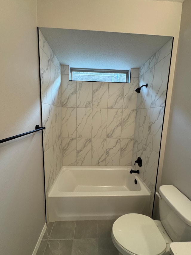 bathroom with tile patterned flooring, tiled shower / bath combo, and toilet