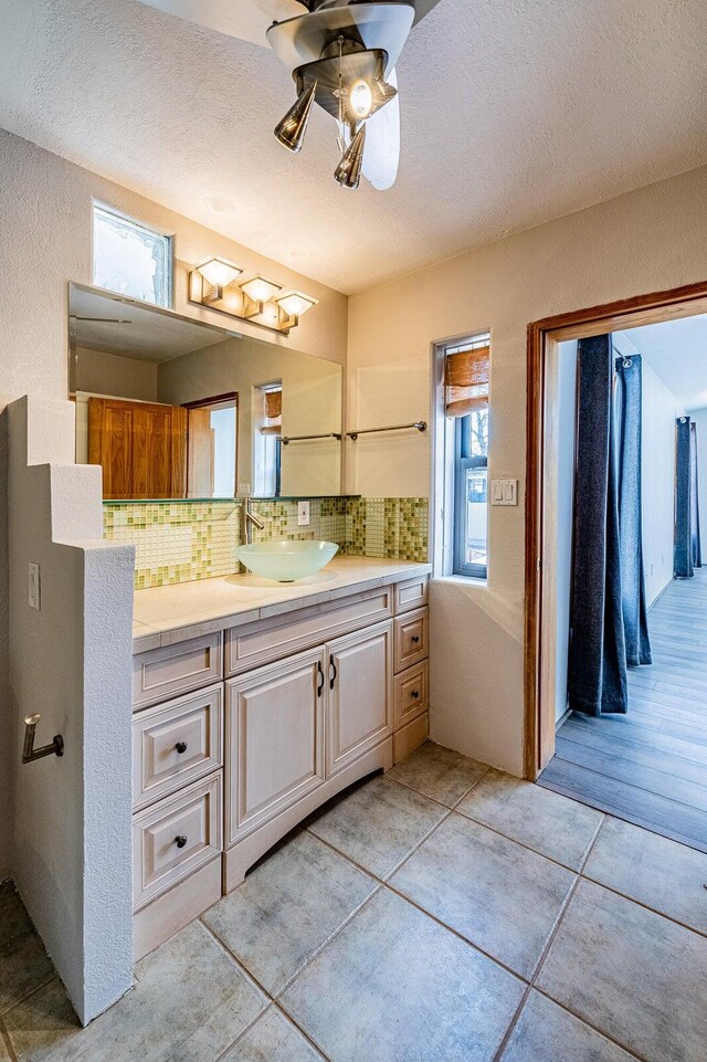 bathroom featuring tile patterned floors, backsplash, vanity, a textured ceiling, and ceiling fan