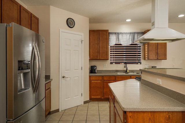 kitchen featuring sink, light tile patterned flooring, island range hood, and stainless steel refrigerator with ice dispenser