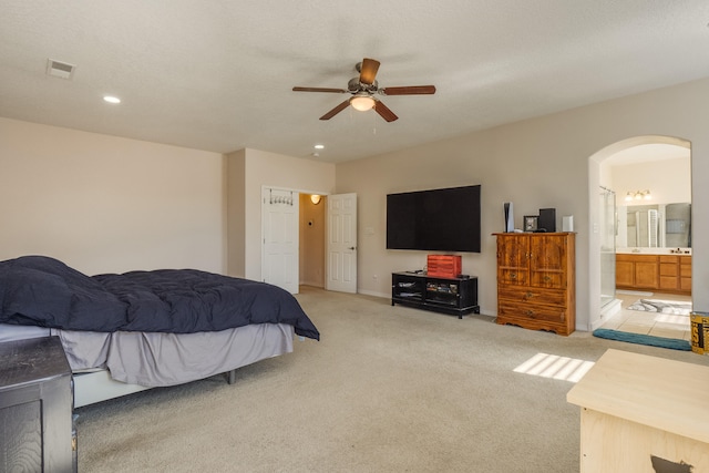 bedroom featuring ensuite bath, light colored carpet, and ceiling fan