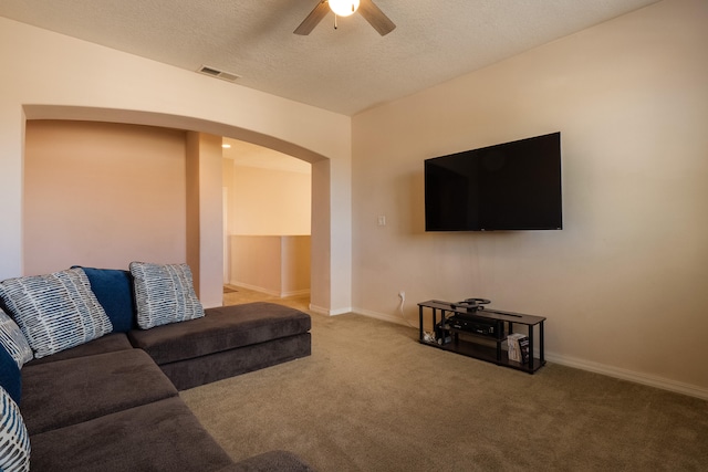 living room with ceiling fan, carpet flooring, and a textured ceiling