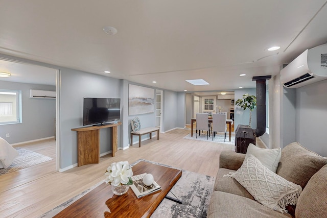 living room featuring light hardwood / wood-style floors, a wall mounted AC, and a skylight