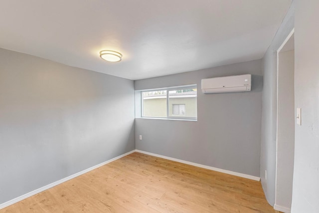 spare room with an AC wall unit and light hardwood / wood-style flooring