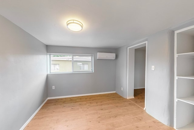 empty room featuring a wall mounted air conditioner and light wood-type flooring