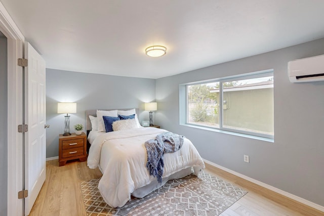 bedroom with an AC wall unit and light wood-type flooring