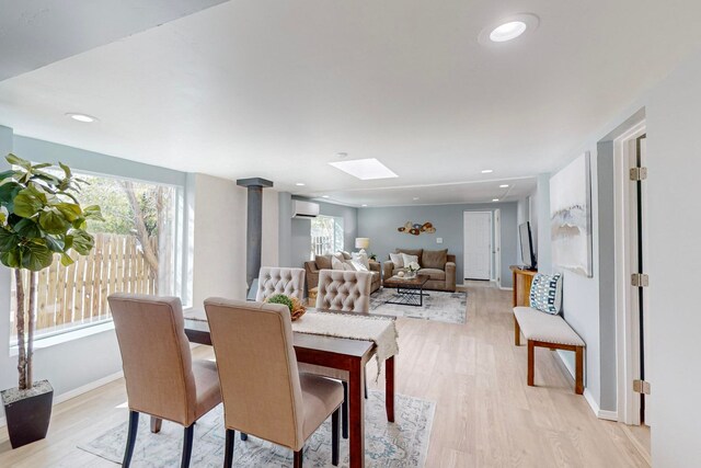 dining room featuring light hardwood / wood-style floors, a wall mounted AC, a skylight, and a wood stove