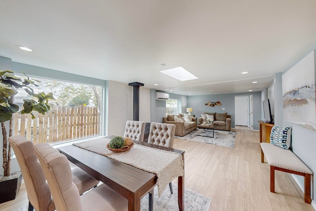 dining space featuring light hardwood / wood-style floors, a wood stove, a skylight, and a wall unit AC