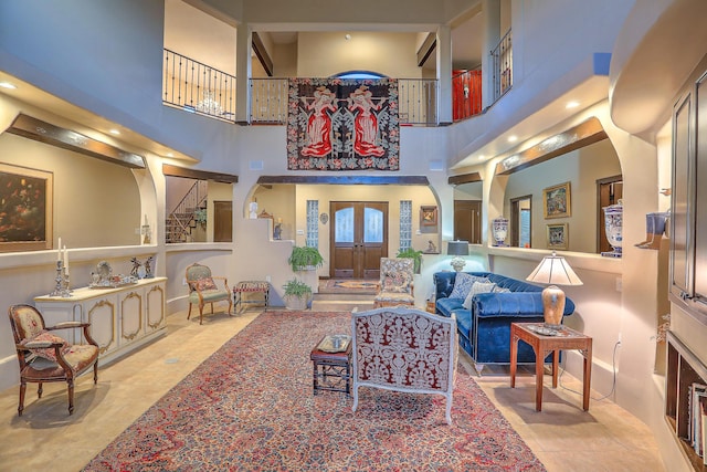 living room with french doors, a towering ceiling, and light tile patterned floors